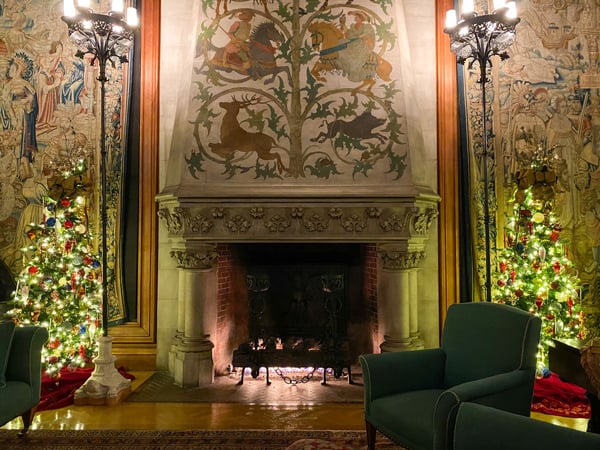 Biltmore Estate home tapestries and Christmas trees on either side of lit fireplace