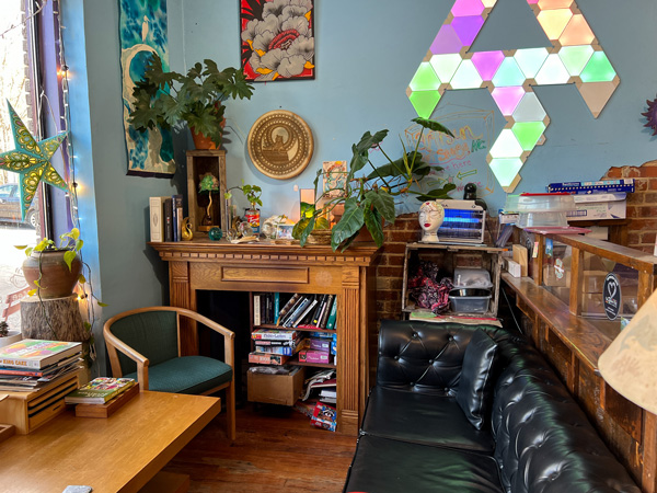 Artisun Gallery and Cafe in Hot Springs NC Lounge area with black sofa, desk with books, and wooden chairs and table