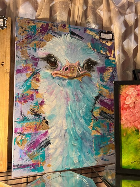 Artisun Gallery and Cafe in Hot Springs, North Carolina painting of ostrich head and face with purple and blue brushstrokes mixed in with white and colorful gold and purple background