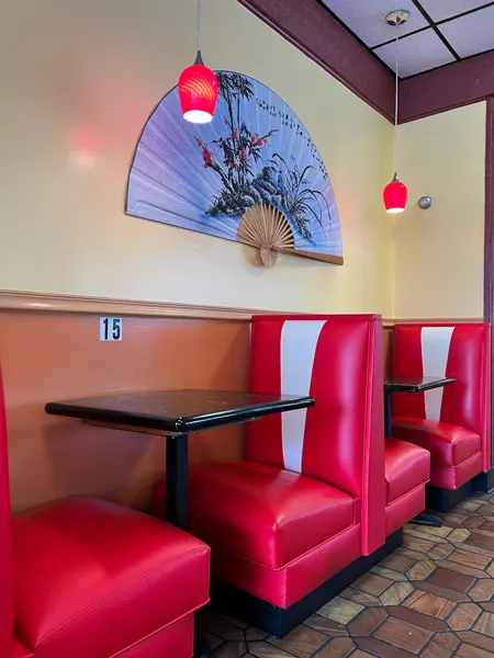 Asaka Japanese Cuisine Biltmore Village Restaurant in Asheville with skinny red and white retro booths with table in the middle and purple Asian-themed fan decoration about tables with red glass lights