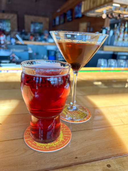 Village Pub Restaurant in Asheville Cocktails with red cider in tall glass and orange brown Manhattan in martini glass on bar