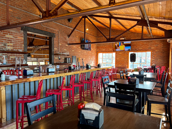 Village Pub Restaurant in Biltmore Village in Asheville NC with photo of upstairs bar with red chairs, brick wall, and TV on wall