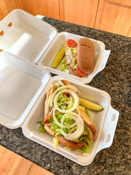 Apollo Flame Asheville Takeout with two styrofoam containers with gluten free and regular subs topped with lettuce, tomato, and onion