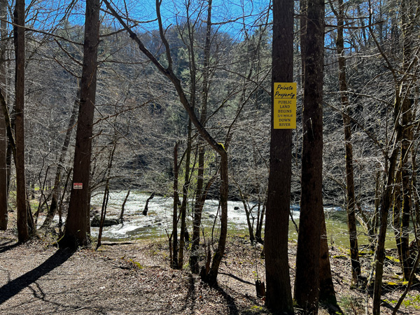 Laurel River Trail Yellow Private Property Signs along trail and riverbank with bare trees