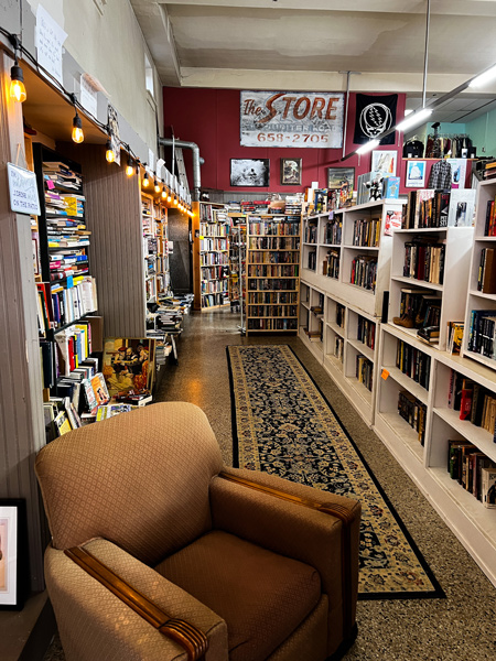 French Broad Exchange in Marshall NC bookstore with old brown armchair and aisle with filled bookshelves on both sides