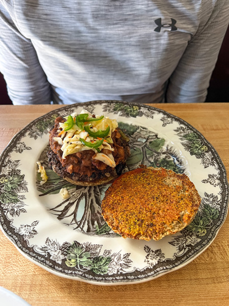 Grateful Organic Diner in Marshall, NC with gluten-free bun, burger, and slaw on vintage like plate on table