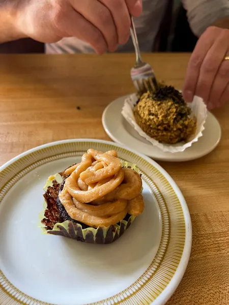 Grateful Organic Diner in Marshall NC Vegan Dessert with chocolate cupcake with orange frosting on plate and gluten-free muffin with a fork in it on another plate
