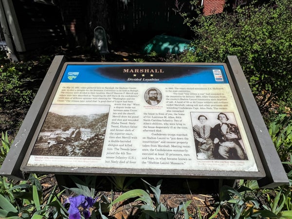 Historic Downtown Marshall, NC Educational sign along sidewalk and surrounded by flowering bush talking about the history of Marshall during the Civil War