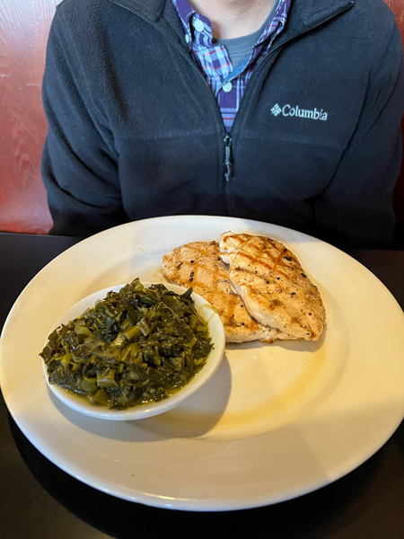 Iron Horse Station Restaurant & Tavern in Hot Springs, NC with white plate filled with grilled chicken and okra on brown table with person's torso in background