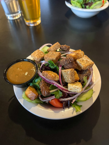 Iron Horse Station Restaurant & Tavern in Hot Springs, NC Salad in white bowl with balsamic dressing on side and croutons, red onion, and tomato on top of green lettuce