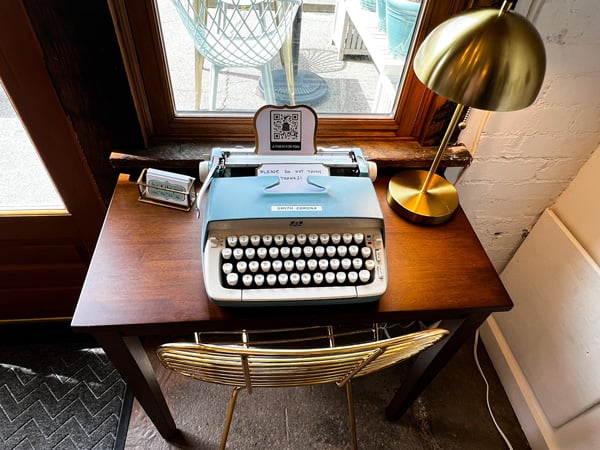 Ivy and the Poet in Marshall NC with blue old school typewriter on brown desk with brass lamp