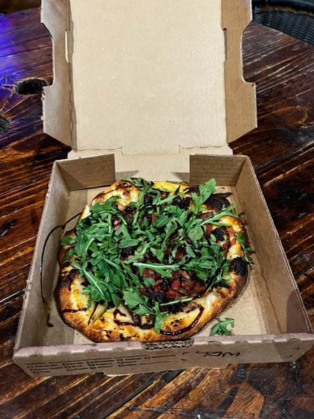 Mad Co Brew House Pizza in Marshall NC with personal sized pizza covered with fig, caramelized onion, arugula, and balsamic in takeaway box
