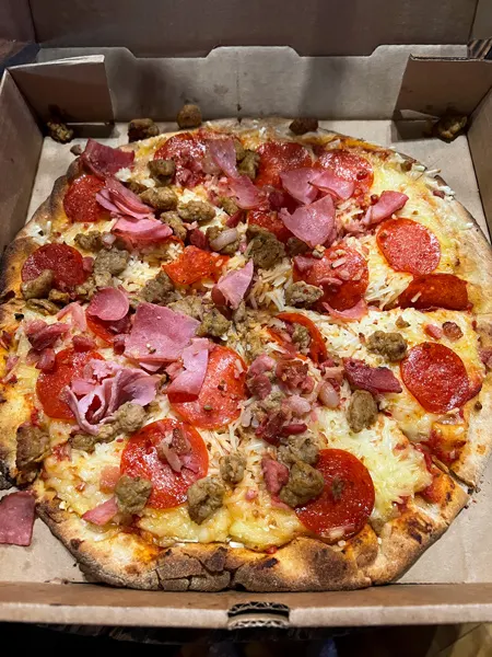 Mad Co. Brew House in Marshall gluten free pizza with vegan cheese, sausage, pepperoni, and ground meat in takeaway box