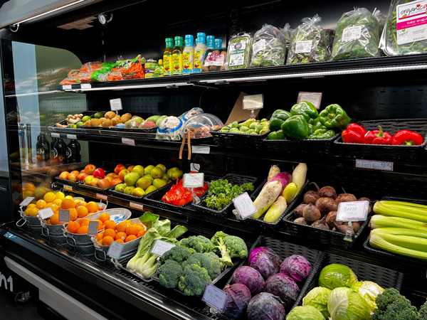 Madison Natural Foods in Marshall produce with fresh vegetables and fruits across four refrigerated but open shelves like lettuce, cabbage, apples, orange, and squash