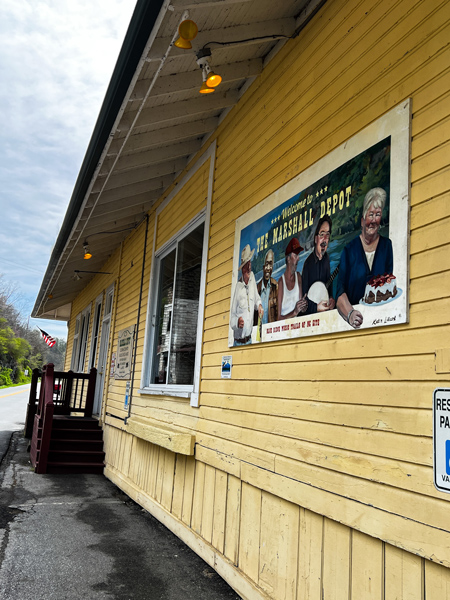 Marshall Depot in NC with image of former yellow train depot with sign and brown wooden staircase