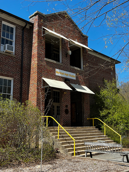 Marshall High Studios in NC with two story brick building, stairs with yellow railing, and bright blue sky