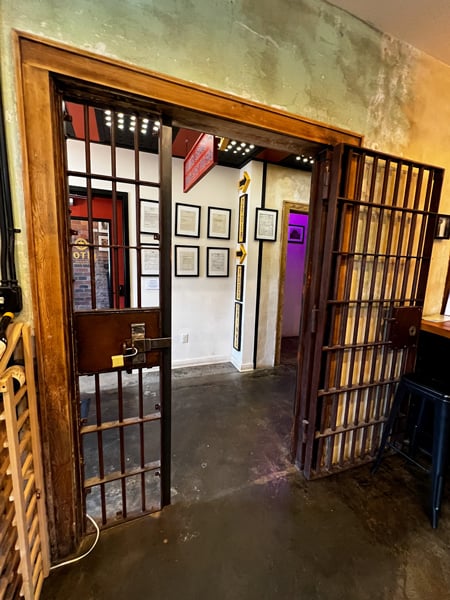 Old Marshall Jai Bar and Hotel with image of historic and old jail bar doorway with framed relics in background