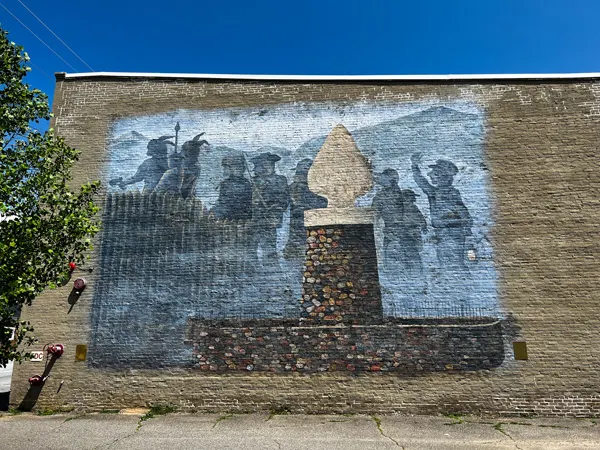 Downtown Old Fort NC Mural with arrowhead statue and Indigenous and soldier shadows