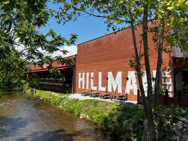 Hillman Beer Brewery and Restaurant in Downtown Old Fort NC with outside facade of red brick building next to the creek with outdoor covered patio seating