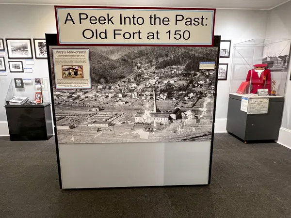 Mountain Gateway Museum in Old Fort NC exhibit with black and white photo blown up of what Old Fort used to look like and old red band school uniform in the background