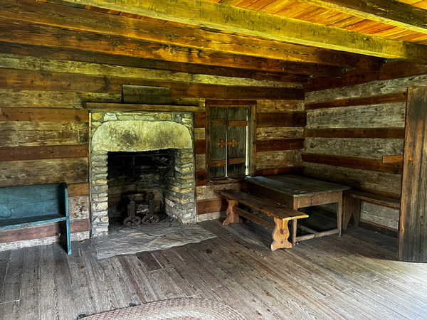 Mountain Gateway Museum in Old Fort, NC Historic Cabin interior with wooden floors and walls along with brick fireplace and old table in the corner