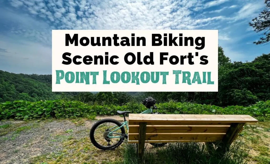 Mountain Biking Scenic Point Lookout Trail in Old Fort NC featured photo with wooden bench, bike leaning on bench, and overlook to blue, gray and green mountains with blue cloudy sky