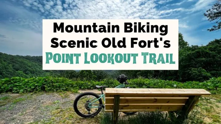 Mountain Biking Scenic Point Lookout Trail in Old Fort NC featured photo with wooden bench, bike leaning on bench, and overlook to blue, gray and green mountains with blue cloudy sky