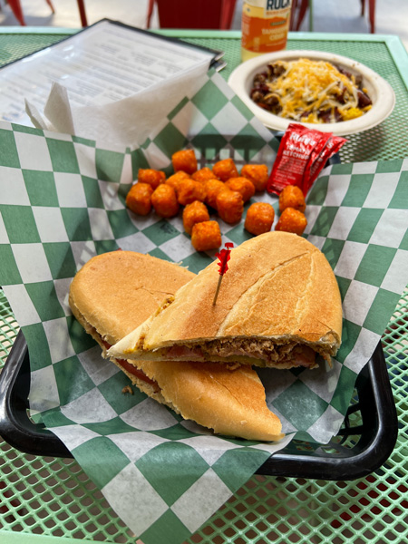 Eluvium Brewing Company Weaverville NC Food with cuban sandwich cut in half, sweet potato tater tots, and breakfast egg bowl with vegan cheese along with beer and Bold Rock hard Cider in bottle