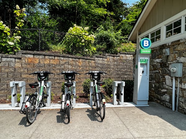Greenville BCycle Bike Rentals along Swamp Rabbit Trail at Greenville Zoo with three ebikes on rack and pay station next to restrooms at zoo entrance