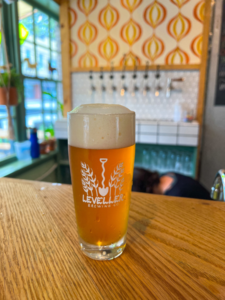 Leveller Brewing Co. Weaverville Brewery with orange-brown beer on bar top with shovel themed taps blurred in background