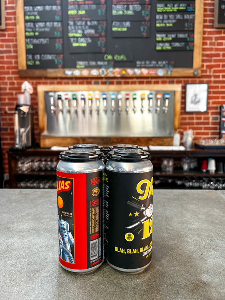 Liability Brewing Co. Greenville SC Gluten Reduced Beer Cans to-go on counter with taps and beer list in background