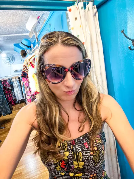Lost and Found Asheville NC with white brunette woman with blonde highlights taking a selfie with big sunglasses and printed dress in dressing room