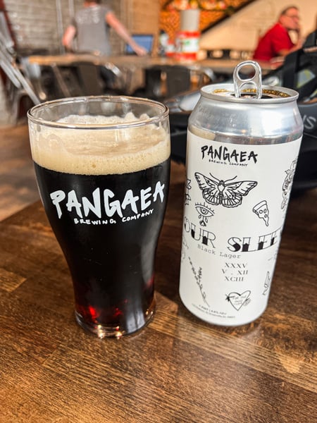 Pangaea Brewing Company Gluten-reduced beer in Greenville SC with white can next to glass filled with dark brown beer