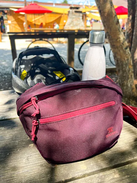 Second Gear Asheville NC Fanny maroon Pack on picnic table with bike helmet and water bottle