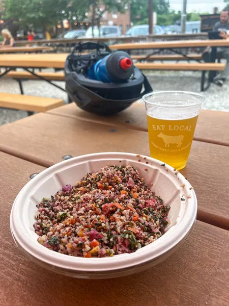 Swamp Rabbit Cafe and Grocery in Greenville SC along the Swamp Rabbit Trail with bowl filled with quinoa and veggies with light yellow beer and helmet and water bottle in background on picnic table