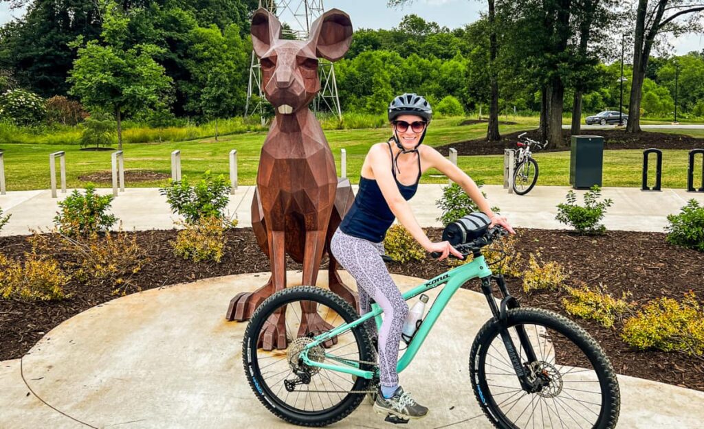 Christine on bike in front of rabbit on Swamp Rabbit Trail