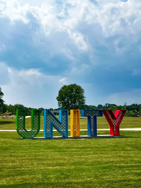 Unity Park in Greenville SC with sign that says Unity with green, blue, yellow and red giant letters on green grass with blue cloudy sky