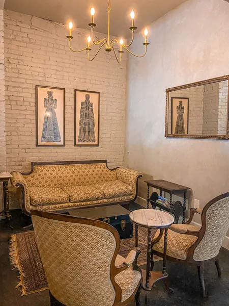 Rowan Coffee Shop Downtown Asheville NC with old cream colored couch and chairs with wall decor like paintings and mirror and chandelier