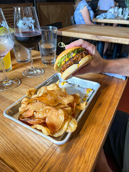 Burger on gluten-free bun with chips and wine in glasses at Wicked Weed BrewPub in Asheville, NC