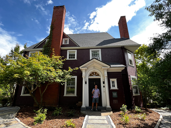 Blind Tiger Asheville Hotel with brown historic house with white trim and man standing out front at door