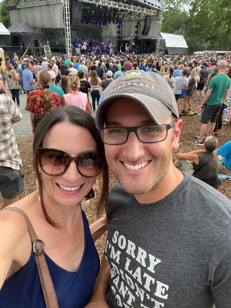 Salvage Station Music Venue in Asheville NC with concert happening with white male and female taking a selfie with band on stage and concert goers around the stage