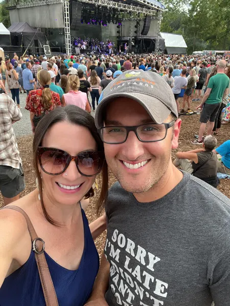 Salvage Station Music Venue in Asheville NC with concert happening with white male and female taking a selfie with band on stage and concert goers around the stage