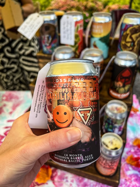 Asheville Greek Festival soy Candle in a beer can with pumpkin design on it and being held up by a white hand