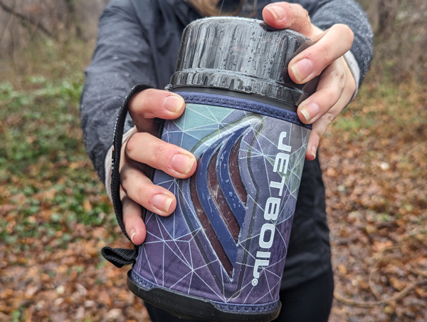 White hands in gray shirt holding a Jetboil Flash Camping and Backpacking Stove Cooking System outside