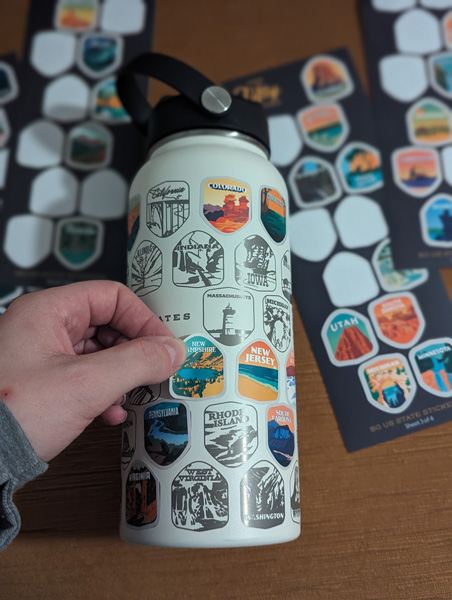 Mont green Stainless Steel Bucket List Water Bottle with white hand placing stickers on it