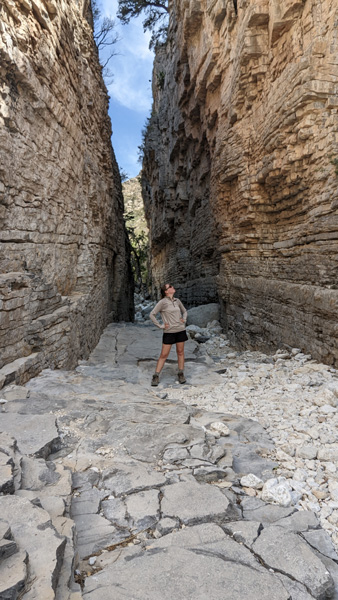 White blonde woman wearing Merino Base Layers and standing between mountains on hiking trail