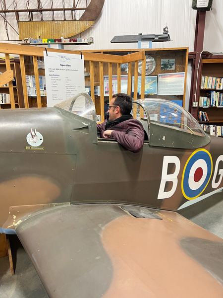 Tom, a white brunette male in purple coat sitting in an older war plane at the Western North Carolina Air Museum in Hendersonville, NC