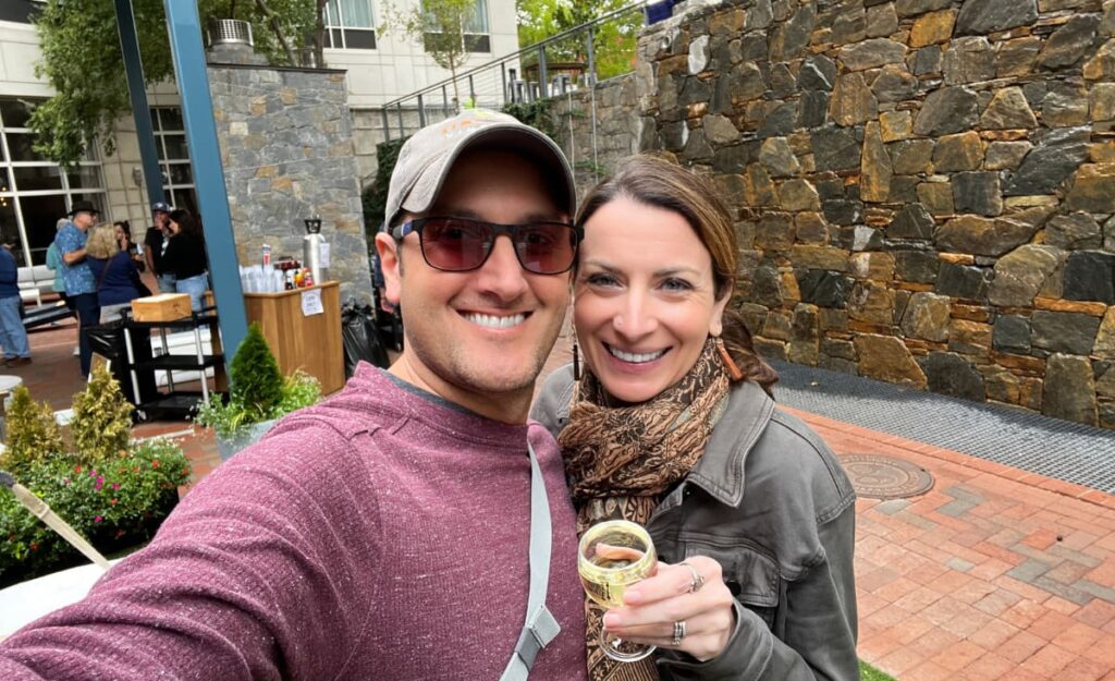 Featured "Asheville Events" article image with Tom and Christine, a white brunette male and female in fall clothes, holding wine near tent at Fall for Greenville Event in Greenville, SC