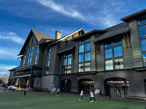 Front of the Grand Bohemian Lodge in Greenville, SC with large windows on a four to five story building and large green space with people on it