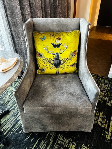 Gray room chair with a yellow beetle and butterfly decorated pillow at the Grand Bohemian Lodge Greenville